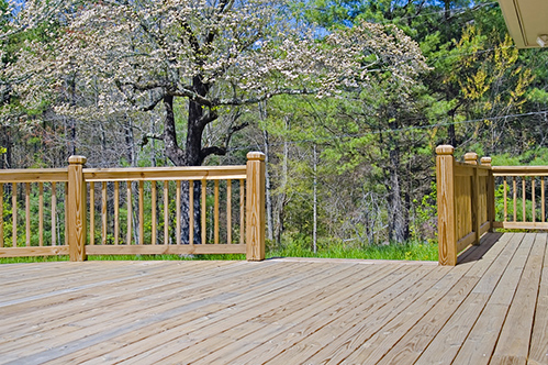 A new wooden deck on the side of a house with Dogwood tree in bloom.